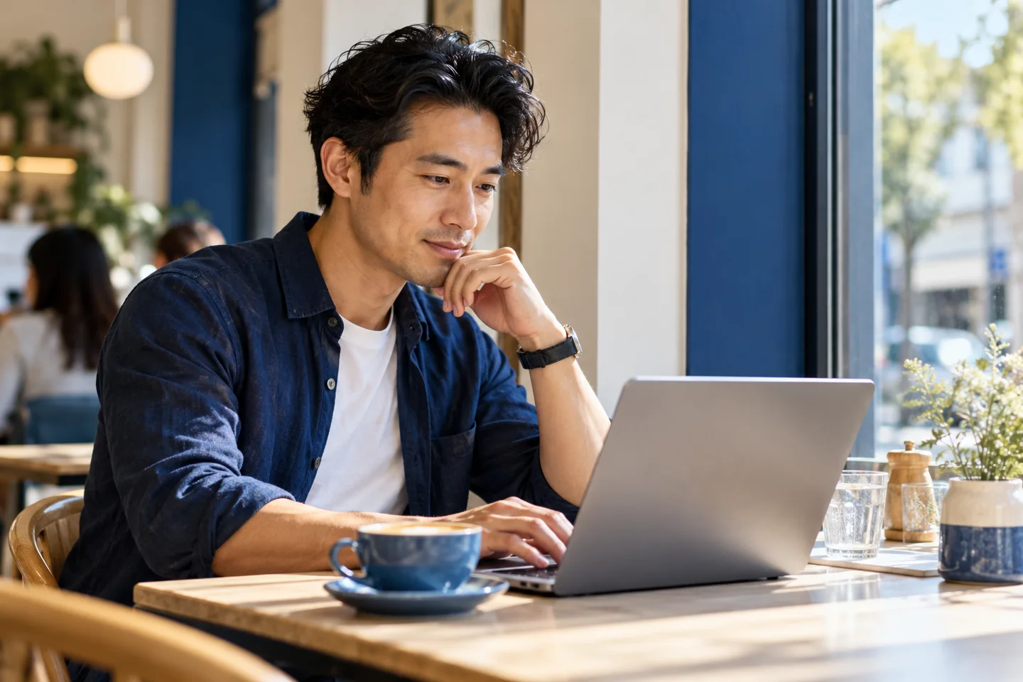 A learner exploring a laptop at a light cafe window